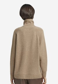 Beige stickad polotröja med avslappnad passform, med ribbade ärmslut och nederkant, samt en mjuk textur. Bakifrån visar den en sömlös design.