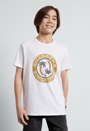 Bela bombažna majica s kratkimi rokavi, ki ima okroglo, večbarvno logotip "Billabong" z palmovimi drevesi in napisom "SINCE 1975". Oblika z okroglim ovratnikom.