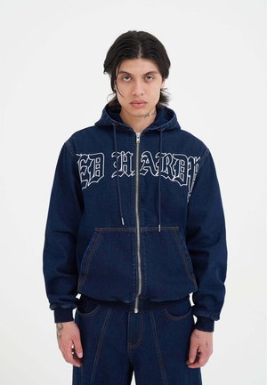Dunkelblaue Denim-Zip-Hoodie mit weißem "ED HARDY"-Text. Verfügt über eine Kapuze mit Kordelzug, Fronttaschen und sichtbare Nähte.