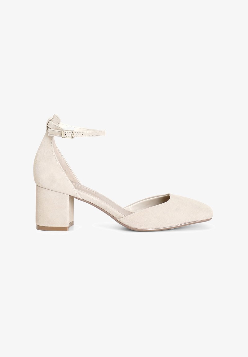 Scarpa beige in suede con tacco a blocco, punta affilata e cinturino alla caviglia. Superficie testurizzata con interno liscio e design minimalista.