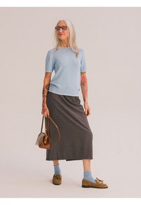 Světle modrý pletený top s krátkým rukávem a bílými detaily, šedá dlouhá sukně, hnědé mokasíny, modré ponožky a malá hnědá kabelka.