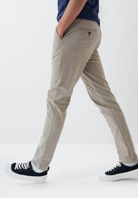 Bežové chinos kalhoty s rovný fit, s bočními kapsami, zadní kapsou na knoflík a hladkou texturou. V kombinaci s černobílými teniskami.