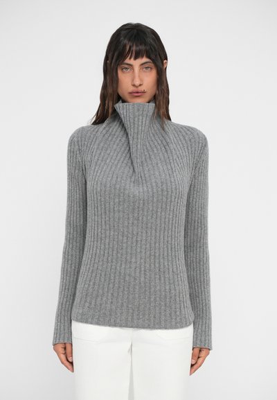 Grauer gerippter Pullover mit hohem Kragen und langen Ärmeln, aus einem weichen Material, kombiniert mit weißen Hosen. einfaches und strukturiertes Design.