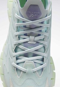 Basket blanche et bleu pastel Reebok avec maille texturée, superpositions en zigzag et lacets bien noués vue de dessus.
