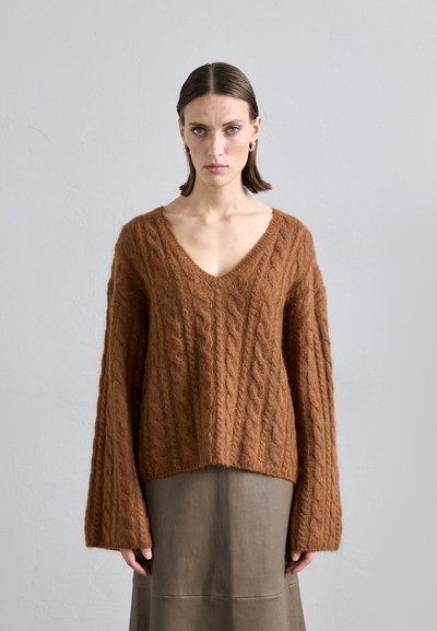 Brun kabelstrikket sweater med V-hals og lange, brede ærmer. Fremstillet af tekstureret stof, med en afslappet pasform og ribbestrikket kant.