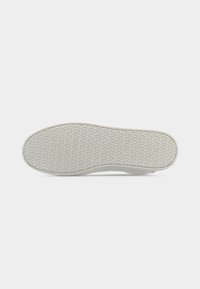 Επίπεδη λευκή σόλα αθλητικού παπουτσιού με υφή σε σχήμα ζιγκ ζαγκ σε απλό ανοιχτό φόντο.