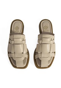 Sandales en cuir beige avec un design tissé et une semelle plate marron. Logo en relief sur la semelle intérieure, texture lisse, style ouvert à l'avant.