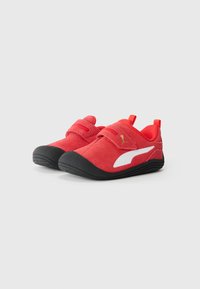 Czerwone buty do wspinaczki z zamszową cholewką, czarną gumową podeszwą i paskami na rzep. Wyposażone w białe logo i tylną pętelkę do łatwego zakładania.