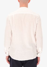 Camicia a maniche lunghe in lino bianco con texture liscia, orlo curvato e polsi con bottoni, che mostra una vestibilità comoda e un design minimale.