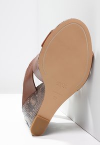 Sandalo a trapezio in pelle marrone con tacco in stampa serpente testurizzata, dotato di suola in gomma flessibile e logo del marchio impresso sulla parte inferiore.