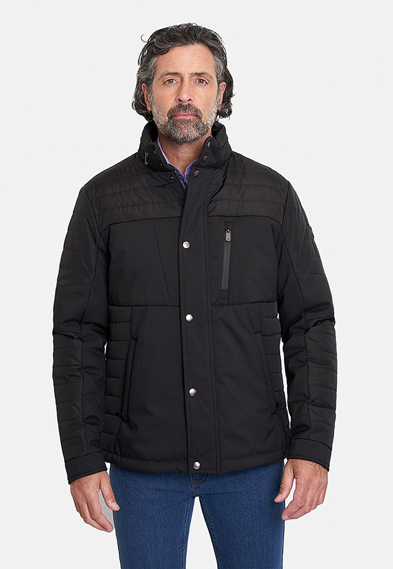 Chaqueta acolchada negra con un alto cuello, cierre frontal con cremallera y cierres a presión. Presenta costuras horizontales y dos bolsillos laterales.
