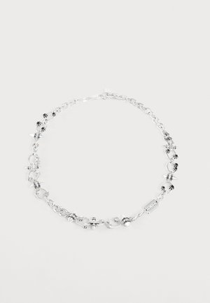 Collier chaîne en argent avec des pointes et de petits charms noirs en forme de main sur un fond blanc uni.
