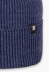 Strickmütze in Marineblau aus weichem Material, mit gerippter Textur und einem kleinen schwarzen Etikett, auf dem "PURE" in Weiß gedruckt ist.