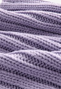 Lavendel strikstof med et tekstureret mønster, der har tykkere, bløde garner vævet i overlappende bølger. Lyse fibre giver et fluffy udseende.