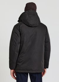 Veste noire isolante avec une grande capuche, tissu texturé et poignets élastiques. Vue de dos montrant une silhouette lisse et des détails de design minimalistes.