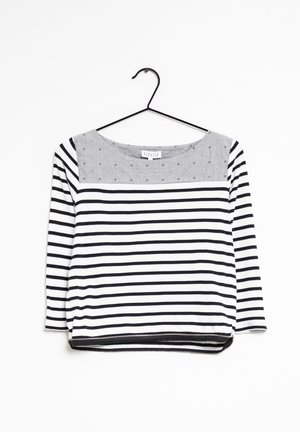 Haut à manches longues rayé noir et blanc avec un col en motif gris et une fermeture éclair noire au bas. Fabriqué en tissu doux et léger.