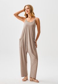 Hellbrauner Overall aus weichem Stoff mit weitem Bein, zwei Vorder taschen, verstellbaren Trägern und einem lockeren Schnitt.