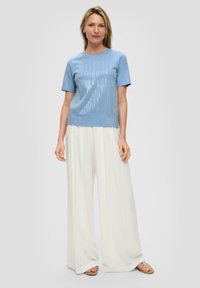 Light blue short-sleeve top with sequined vertical stripes, paired with white wide-leg pants. Smooth fabric and relaxed fit.