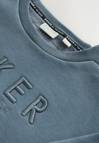 Blaues Sweatshirt mit Rundhalsausschnitt, versehen mit einem strukturierten, geprägten "BAKER"-Logo. Hergestellt aus weichem Stoff mit gerippten Kanten und einem Label innen.