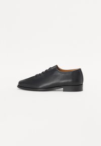 Black leather shoe with a smooth texture, rounded toe, six eyelets, and a low heel. The interior is brown leather. Simple design.