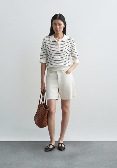 Λευκό πλεκτό πόλο με οριζόντιες ρίγες, συνδυασμένο με κρέμα κοντο παντελόνι, καφέ πλεγμένη τσάντα και μαύρες φλατ. Απλή, καθημερινή εμφάνιση.