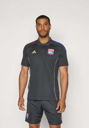 Polo sportif gris foncé avec des accents dorés, présentant des rayures de couleur rouge et bleue sur les épaules, et un logo sur la poitrine.