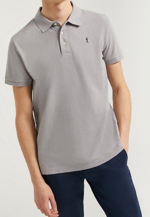Graues Poloshirt aus strukturiertem Stoff, mit einer Zwei-Knopf-Leiste und kurzen Ärmeln. Das Shirt hat ein kleines Logo eines Golfspielers auf der linken Brust.