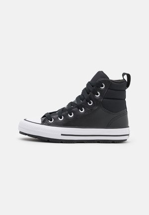 Sneakers negre cu guler înalt, realizate dintr-un material texturat, cu vârf din cauciuc alb, talpă albă în contrast și un design clasic cu șireturi.