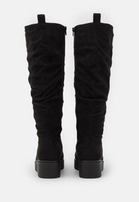 Czarne kozaki do ud z miękkiego zamszu, charakteryzujące się gładkim, dopasowanym krojem, z niewielkim obcasem i bocznym zamkiem błyskawicznym.