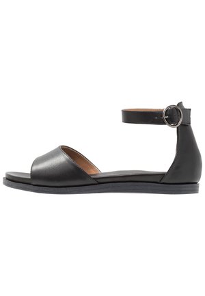 Sorte lædersandaler med åben tå, ankelrem og rund spænde. Flad sål og glat tekstur; minimalistisk design.