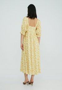 Geel maxi-jurk met een zebraprint, geplooide mouwen en een vierkante achterkant. Gemaakt van lichte stof, met een smocked taille.