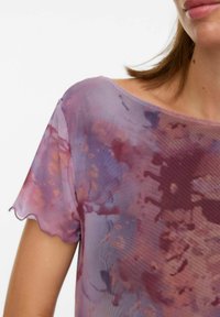Top leggero e trasparente di colore viola con un motivo tie-dye in tonalità di rosa e arancione, finiture a scallop sulle maniche e ampiole scollature.