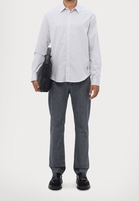 Camisa a rayas blanca y azul, jeans de denim grises, zapatos negros, sosteniendo un bolso de cuero negro. Diseño simple y ajustado con una silueta relajada.