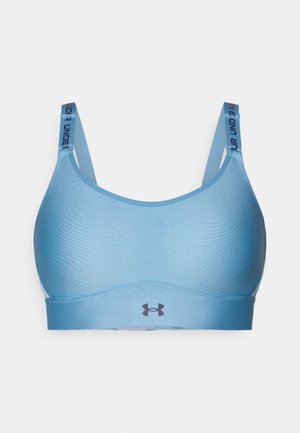 Soutien-gorge de sport bleu clair avec des bretelles réglables, une texture lisse, une large bande et un logo Under Armour noir à l'avant et sur la bretelle.