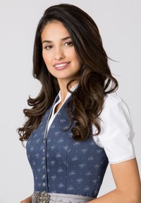 Traditional dress featuring a blue patterned bodice, silver buttons, and a white blouse. Accented with a grey belt and ornate buckle.