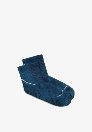 Paire de chaussettes chevilles bleues avec bords côtelés et motifs en zigzag blancs sur fond blanc.