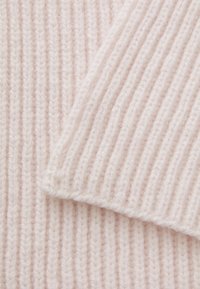 Ribbed knit fabric in soft pink hue, showcasing fine texture and seams. The material appears light and cozy, with neat stitching detail.