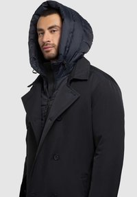 Meeste must peacoat, millel on eemaldatav, polsterdatud mereväe sinine kapuuts. Omab nööpide eesmist kinnitust, küljetaskuid ja sileda, tekstuuriga viimistlust.