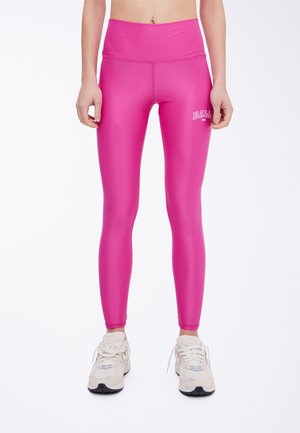 Leggings de talle alto en color rosa, fabricados con material elástico, que presentan un logo en el muslo y una textura suave y brillante.