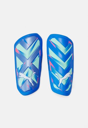 protège-tibias de football bleus avec un motif en chevron agrémenté de touches de vert et de rose. Présente un logo Puma blanc et une finition en plastique lisse.