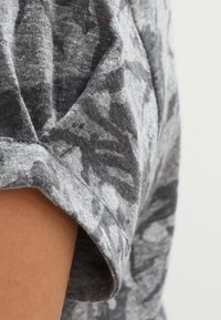 Pánské tričko s krátkým rukávem šedé barvy, vyrobené z texturované látky s abstraktním vzorem v tmavších odstínech šedé a volným střihem.