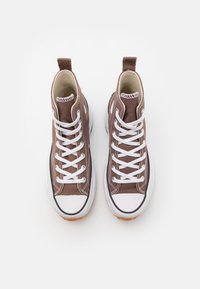 Brązowe wysokie trampki z białymi sznurowadłami, gumowymi czubkami i kontrastującymi białymi przeszyciami. Podeszwa zewnętrzna w kolorze gumy z teksturowanym bieżnikiem.