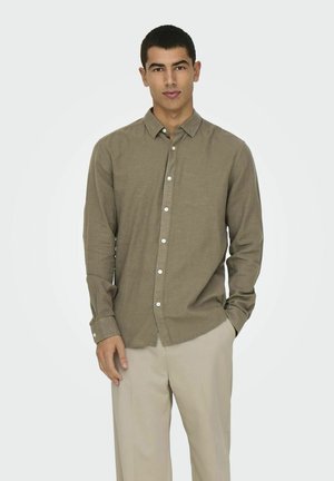 Light brown button-up shirt made of textured fabric with a collar and white buttons, paired with beige trousers. No patterns or accents visible.
