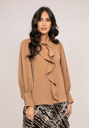 Blouse légère marron avec un détail froncé à l'avant, des manches ballons longues et un col à boutons. Jupe à motif avec des rayures noires et beiges.