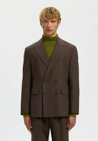 Pruun kaherealine bleiser notšiga kraedega, mustade nuppude, küljetaskute ja all roheline soonikkoega kõrge kaelusega kampsun.