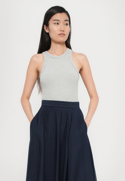 Grå ribbet tanktopp med høy hals, kombinert med en marineblå plisserte skjørt med striper og sidelommer.