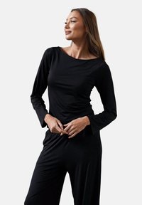 Czarny, długi rękaw, wykonany z miękkiego materiału, z szerokim dekoltem i dopasowanym krojem, podkreślający gładką teksturę i elegancki kształt.