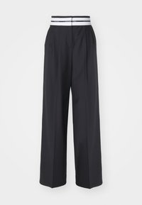 Schwarze weit geschnittene Hose mit flachem Bund, zwei Falten und einem elastischen Bund, der ein weiß-schwarz gestreiftes Detail aufweist.