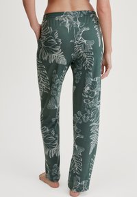 Grüne Loungehosen mit floralem Muster, elastischemBund und Seitentaschen. Hergestellt aus weichem Material, mit weißen botanischen Illustrationen.