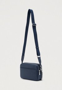Torba preko ramena u mornarsko plavoj boji s teksturiranim finišem, ima zatvarač na patentni zatvarač, podesivi remen i srebrni ukras od metalnog pribora.